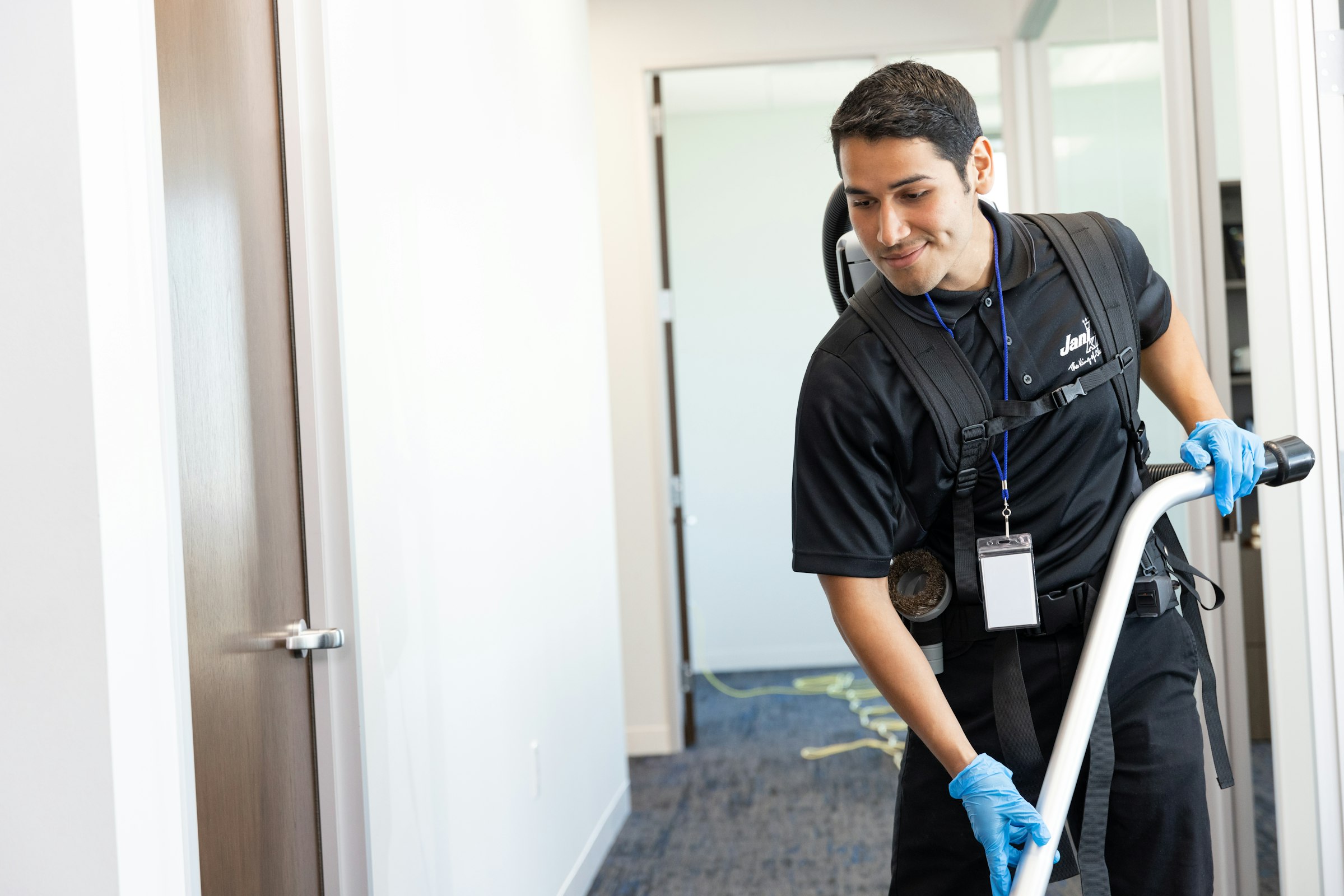 Jani-King franchisee vacuuming carpet in a customers workplace